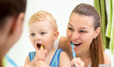 Mother training his child to brush teeth